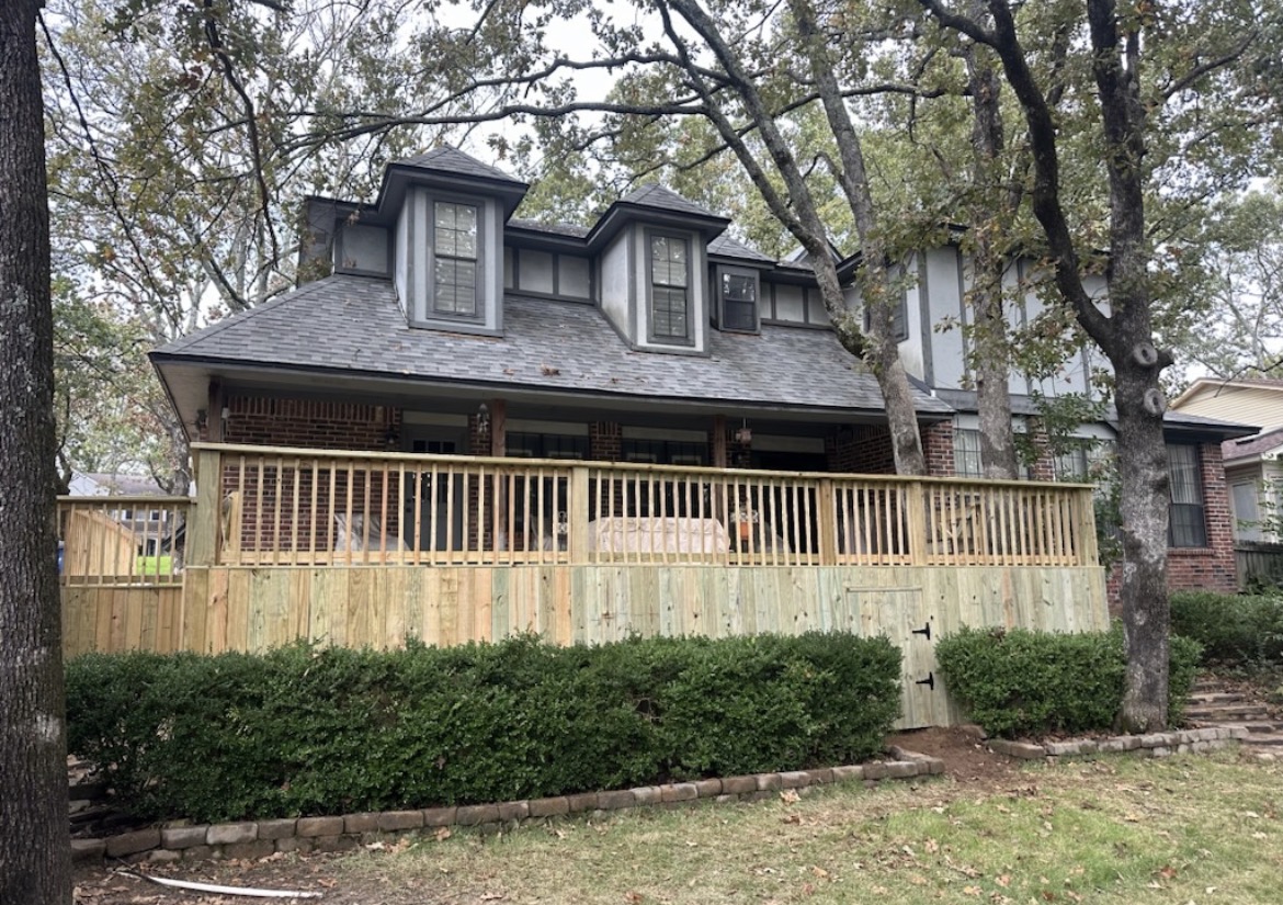 Freshly built wood deck and railing wrapping a covered porch on a two-story home in Springdale, AR