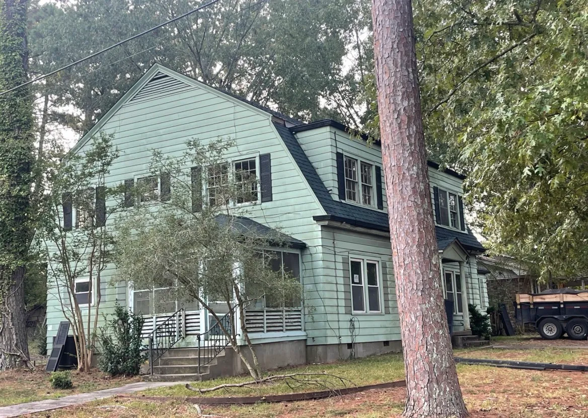 The same home after exterior painting and a new black roof, with fresh, clean sage-green siding