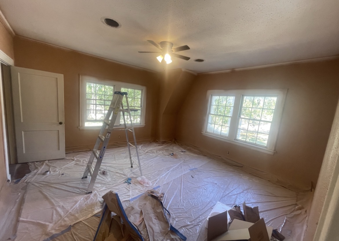 Bathroom mid-renovation with walls prepped for paint, fixtures protected, and floors covered during interior work